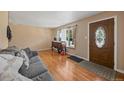 Bright living room with wood-look floors, a sofa, and a front door with an oval window at 11192 E 7Th Ave, Aurora, CO 80010