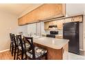 Functional kitchen featuring a breakfast bar, black appliances, and wood cabinetry at 9411 W 89Th Cir, Westminster, CO 80021