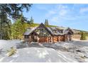 Beautiful home featuring wood accents, stone detailing, and a spacious driveway surrounded by mature trees at 50 Cooney Ct, Breckenridge, CO 80424