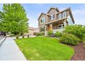Well-maintained front yard with lush green lawn, garden beds, and a mature tree accenting the property at 10235 Rustic Redwood Ln, Highlands Ranch, CO 80126