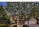 Beautiful exterior of a two-story home with stone and brick accents, a large tree, and an attached two-car garage at 5390 S Geneva St, Englewood, CO 80111