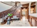 Elegant foyer featuring a staircase with wood paneling, tile floors, and a decorative bench at 5390 S Geneva St, Englewood, CO 80111