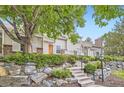 Inviting front exterior featuring tan siding, stone landscaping, green shrubs, and well-maintained stairs at 2902 W Long Cir # B, Littleton, CO 80120