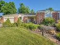 Landscaped front yard featuring a brick home with flowering plants and a well-maintained lawn at 6844 S Detroit Cir, Centennial, CO 80122