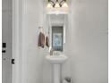 Clean powder room with a pedestal sink and decorative mirror at 19155 Robins Dr, Denver, CO 80249