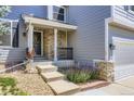 Close-up of the front porch with stone details, concrete steps, and manicured landscaping at 9890 Gaylord St, Thornton, CO 80229