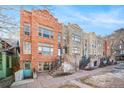 Three-story row house with red and gray stone facade with entrance stairs and a sidewalk at 1610 N Humboldt St # 1/2, Denver, CO 80218