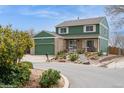 A two-story home with green siding, a brick facade, and a two-car garage and landscaped yard at 483 S Kingston Cir, Aurora, CO 80012