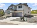 Side view of the two-story home with an attached two car garage, and well-maintained yard at 1694 Fox Trotter Pt, Castle Rock, CO 80104