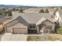 Inviting home exterior featuring stone accents, a covered entry, well-maintained landscaping, and an attached two-car garage at 1520 Symphony Hts, Monument, CO 80132