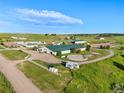 Aerial view of a horse farm featuring multiple barns, paddocks, a horse trailer, and a pristine green landscape at 39681 Swift Creek Cir, Elizabeth, CO 80107