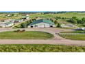 Aerial view of a barn with multiple bays surrounded by well-manicured grounds, fencing, and open fields at 39681 Swift Creek Cir, Elizabeth, CO 80107