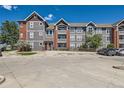 Apartment building featuring gray siding, brick accents, multiple floors, and a convenient parking area at 14251 E 1St Dr # 305, Aurora, CO 80011