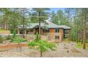 Wood and stone home with rock landscaping and a brick retaining wall in a wooded area at 7597 Molas Ct, Larkspur, CO 80118
