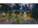 Wood and stone home with rock landscaping and a brick retaining wall in a wooded area at twilight at 7597 Molas Ct, Larkspur, CO 80118