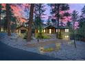 Stunning wood and stone home with rock landscaping and a brick retaining wall at twilight at 7597 Molas Ct, Larkspur, CO 80118