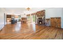 Spacious living room with hardwood floors, brick fireplace, and adjacent kitchen and dining areas at 10490 W 78Th Ave, Arvada, CO 80005