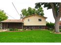 Backyard featuring a lush lawn, mature trees, and a charming covered patio area at 11823 Williams Way, Northglenn, CO 80233