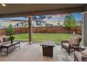 Relaxing backyard patio with a cozy fire pit and beautifully landscaped lawn with string lights for evening ambiance at 16400 Alberta Dr, Parker, CO 80134