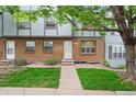 Charming townhome exterior with brick facade, green lawn, and mature tree at 670 Winona Ct # 38, Denver, CO 80204