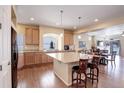 Open kitchen boasts stainless steel appliances, granite countertops, an island with seating, and hardwood floors at 1060 Arrowhead Ct, Erie, CO 80516