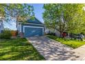A blue home featuring a two-car garage and driveway with shade trees on a sunny day at 19884 E Villanova Pl, Aurora, CO 80013