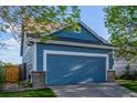 Close up of a blue two-car garage with brick features, a cement driveway and grass lawn at 19884 E Villanova Pl, Aurora, CO 80013