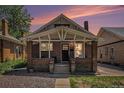 Charming brick home featuring a cozy front porch with white support beams, showcasing classic architectural details at 4536 Beach Ct, Denver, CO 80211
