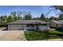 Well-maintained home featuring a lush green lawn, mature trees and an attached garage at 6931 W 75Th Pl, Arvada, CO 80003