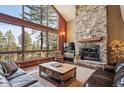 Inviting living room features a stone fireplace, large windows with stunning views, and comfortable leather seating at 7837 S Settlers Dr, Morrison, CO 80465