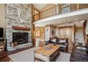 Spacious living room with stone fireplace, hardwood floors, and a second-story balcony, creating an open and airy feel at 7837 S Settlers Dr, Morrison, CO 80465