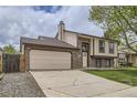 Two story home with brick and neutral siding, a two car garage, and long driveway at 9374 W Friend Dr, Littleton, CO 80128