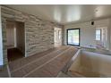 Open-concept living room featuring a decorative stone wall, bright interior paint, and access to the outdoor space at 1555 Arrowpoint Ct, Franktown, CO 80116