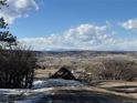 Expansive landscape view showcasing rolling hills, scattered homes, and majestic snow-capped mountain peaks in the distance at 1555 Arrowpoint Ct, Franktown, CO 80116