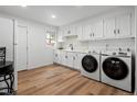 Bright laundry room featuring a washer and dryer, white cabinetry, and modern fixtures at 2621 S Federal Blvd, Denver, CO 80219