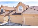 Charming home featuring a tan exterior, two-car garage, tiled roof, and arched window on the upper level at 5976 S Jellison St # E, Littleton, CO 80123