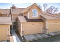 Charming home featuring two-car garage, tan siding, beautiful tiled roof, and lovely arched window above the garage at 5976 S Jellison St # E, Littleton, CO 80123