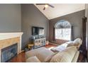 Inviting living room features a vaulted ceiling, fireplace, plush seating, and a large window that offers ample light at 5976 S Jellison St # E, Littleton, CO 80123