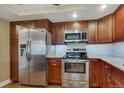 A well-lit kitchen featuring stainless steel appliances, wooden cabinetry, and granite countertops at 13961 E Marina Dr # 314, Aurora, CO 80014