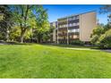 Exterior view of the property showcasing its well-maintained lawn, mature trees, and multi-story facade at 7040 E Girard Ave # 207, Denver, CO 80224