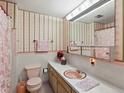 Retro pink bathroom featuring a coordinated sink, toilet, and patterned wallpaper at 3018 S Depew St, Denver, CO 80227