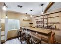 Basement wet bar featuring a stone counter, wood accents, and overhead pendant lighting fixtures at 602 Mathews Way, Erie, CO 80516