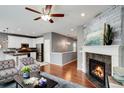 Open-concept living room featuring a fireplace, ceiling fan, and seamless flow into the modern kitchen at 602 Mathews Way, Erie, CO 80516