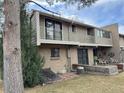 Backyard showcasing an upper balcony, lower deck and mature landscaping at 6475 S Arapahoe Way, Littleton, CO 80120