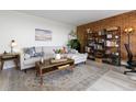 Cozy living room with a comfortable sofa, rustic coffee table, brick accent wall, and shelving at 955 Eudora St # 1606, Denver, CO 80220