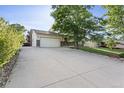 View of a long driveway leading to a two-car garage and manicured front lawn at 874 Mercury Cir, Lone Tree, CO 80124