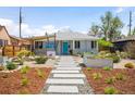Charming gray bungalow featuring a modern walkway, beautiful landscaping, and a bright blue front door at 822 Poplar St, Denver, CO 80220