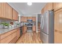 Well-lit kitchen with wood cabinets, stainless steel appliances, granite countertops, and convenient access to the staircase at 6611 Lamar St, Arvada, CO 80003