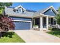 Charming blue two-story home with landscaped yard, solar panels, and covered porch with seating at 1038 Mircos St, Erie, CO 80516