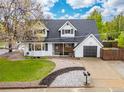 Two-story home with a well-maintained lawn, dormer windows, a cozy front porch, and a single-car garage at 12212 W 60Th Pl, Arvada, CO 80004